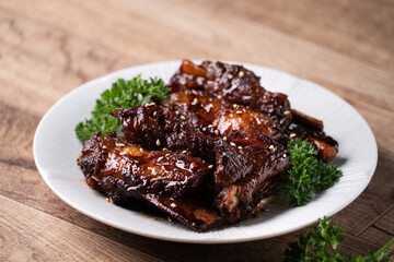 Barbecue pork spare ribs in a plate on wooden table background.