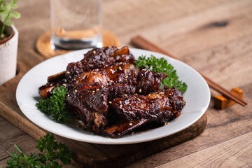 Barbecue pork spare ribs in a plate on wooden table background.