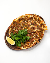 Italian pizza with minced meat. Cut into two halves on wooden board with slice of lemon and parsley. Italian food. Isolate on white background. Copy space.