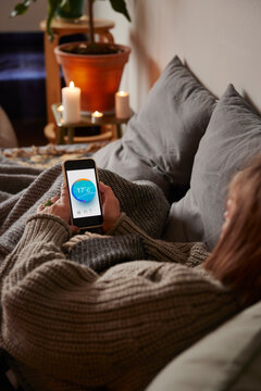 Woman lying in bed and using temperature app