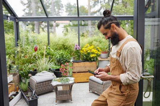 Man in greenhouse using cell phone