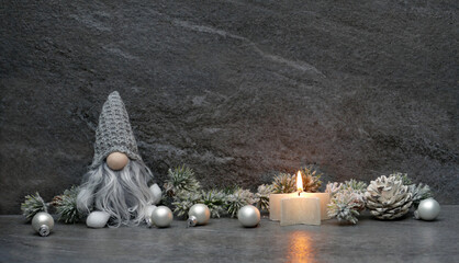 Weihnachtshintergrund: Wichtel mit Kerzen und Weihnachtsschmuck vor einer grauen Marmorwand.