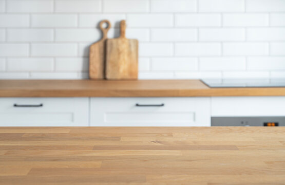 ..Wooden oak countertop with free space for mounting a product or layout against the background of a blurred white kitchen.