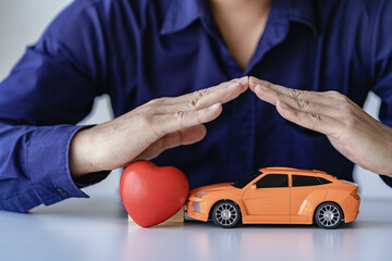 Small car covered by hand, auto insurance concept.