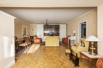 A spacious living room in a house with vintage furniture with an old television, a white wooden bookcase and a yellow fabric sofa with an industrial parquet duvet