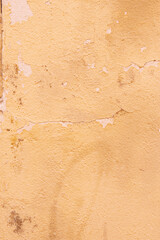 Rough surface of a wall with peeling paint of pale cream yellow color