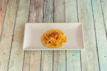 A Mexican chicken tinga taco on a white porcelain tray