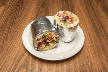 A wonderful burrito stuffed with rice, sautéed vegetables and red beans wrapped in aluminum foil split in half