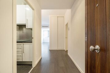 Entrance hall of a house with a solid wood door, access in the first instance to a kitchen and then to a corridor with built-in wardrobes and windows through which light enters in abundance