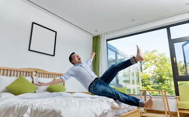 Excited man jumping to the bed