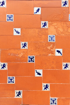 Pavimento del patio de una casa espa&ntilde;ola con baldosas cer&aacute;micas y azulejos de olambrillas. Paramento decorativo que combina losetas rojas y peque&ntilde;os azulejos de siluetas azules sobre fondo blanco