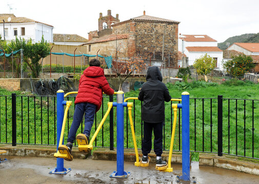 Ni&ntilde;os jugando en un aparato gimn&aacute;stico de caminar o balanceo en parque a las afueras del pueblo
