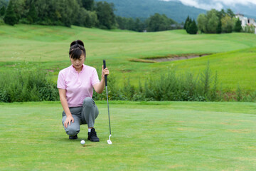 Fototapeta premium Female golfer crouching looking the golf ball