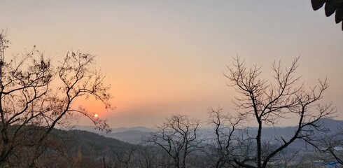 Obraz premium Dramatic sunset and sunrise with sun flare over mountain valley morning twilight evening sky. The incandescent round sun goes into the sunset.