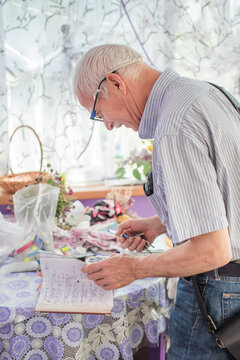 The Old Man Flips Through A Notebook With Notes. Running A Business For Seniors. Memory Problems In Men After 65 Years.