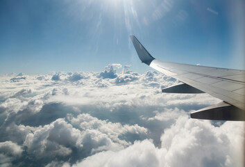 Wing of airplane flying above clouds