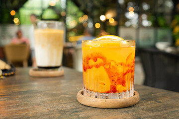 A glass of orange juice squash mixed with red strawberry syrup served with sunkist orange garnish...