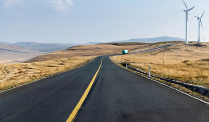 Fototapeta na wymiar Empty asphalt highway road surrounded by fields with windmills
