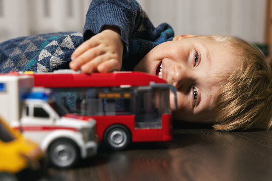 little boy playing with toy cars on the floor at home