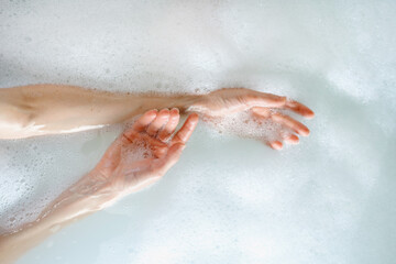 Woman hands over hot water in bubble bath