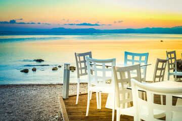 seaside cafe tables near beach at sunset, Corfu Greece, toned