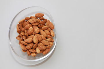 small grains of natural brown almonds in a decorative glass plate