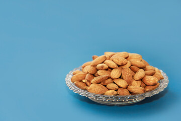 small grains of natural brown almonds in a decorative glass plate