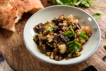 Fried chopped eggplant with garlic and bread crumbs in a bowl on wooden table. Vegetable gourmet snack or appetizer. Selective focus - 553753421