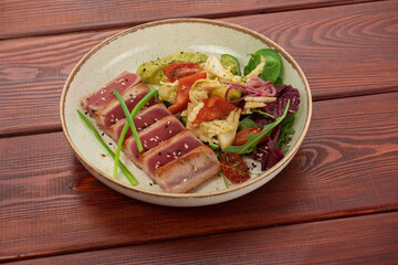 Grilled salmon steak with potatoes and vegetables on a wooden table