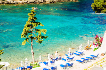 Paleokastritsa beach bay with sunbeds and Ionian sea clear water on Korfu, Greece, toned