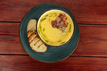 cream soup with bacon in a cup on a wooden table