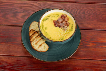 cream soup with bacon in a cup on a wooden table