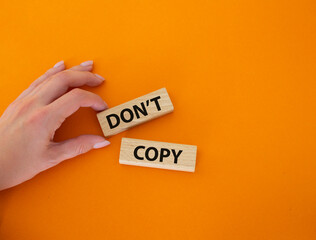 Don't copy symbol. Wooden blocks with words Don't copy. Beautiful orange background. Businessman...