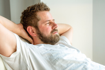Obraz premium Portrait of a casual tired man resting sitting on a couch at home