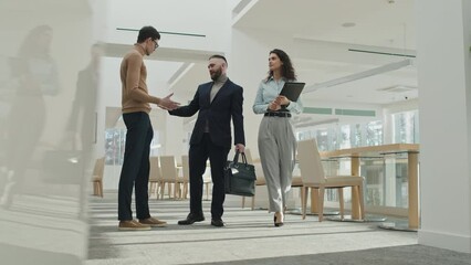 Low angle view of young businessman shaking hands with his colleague and saying goodbye after business meeting