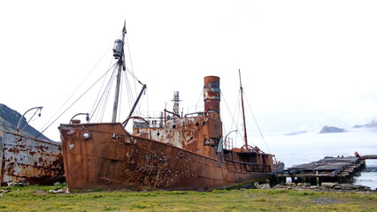 Old, rusted whaling and sealing ship by an old pier at the old whaling station at Grytviken, South Georgia Island - obrazy, fototapety, plakaty