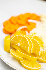 Sliced lemons, onions, garlic and carot on the plate ready for cooking