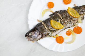 Baked trout served on the plate with vegetables