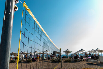 Fototapeta premium Volleyball net on sand in summer background. Outdoor leisure games. Active lifestyle on beach with sand near sea or ocean with sky.