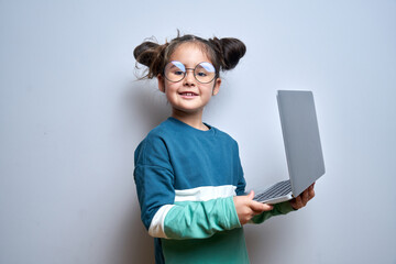 Little caucasian child girl smiles and holds laptop in her hands isolated on white background