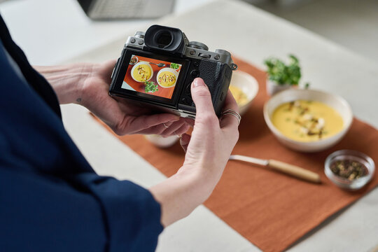 Close-up of woman photographing two bowls of soup with professional camera