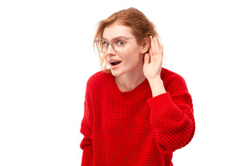 Young redhead woman in casual wear smiling and holding hand near ear, listening carefully, hearing...