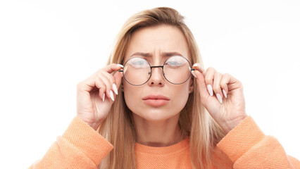 Blonde young woman wearing glasses squinting while looking at camera isolated on white background. Vision problems concept - obrazy, fototapety, plakaty