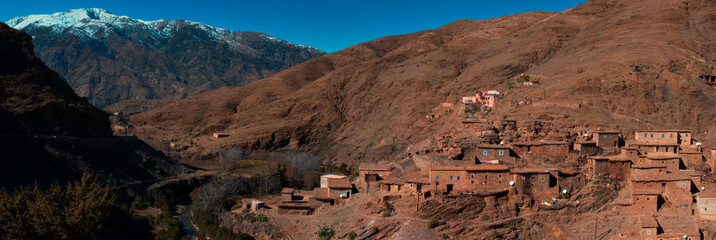 Panoramic view of Small village in the middle of Atlas mountains, Morocco with snow capped mountain in background
