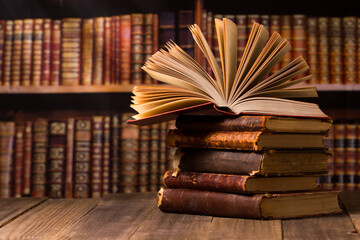 Composition with vintage old hardback books, diary, fanned pages on wooden deck table and red background. Books stacking. Back to school. Copy Space. Education background.	