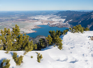 view from snowy Herzogstand mountain top to lake Kochelsee, winter landscape bavaria