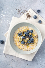 Oatmeal porridge with some fresh blueberries and honey in ceramic bowl, top view