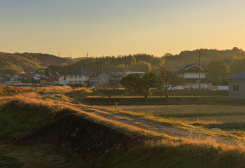 Early morning light hits dirt road through small Japanese town