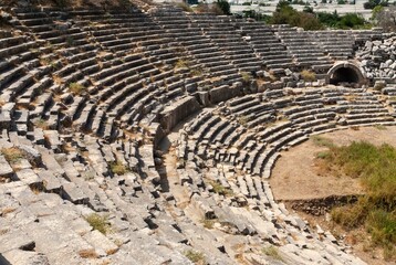 Turkey. Fethiye. Ruins of ancient Greek amphitheater against backdrop of mountains. Sunset. Around amphitheater are columns and walls destroyed by time. Blurred background. Selective focus.