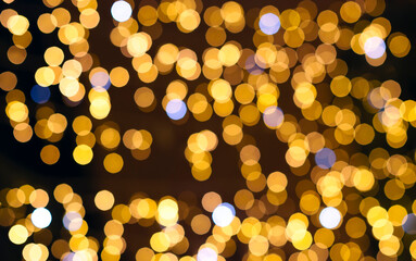 Golden blurry lights with blue and white highlights and space for a copy. Golden bokeh on a dark background, decor, print, festive photo with blurred lights, highlights